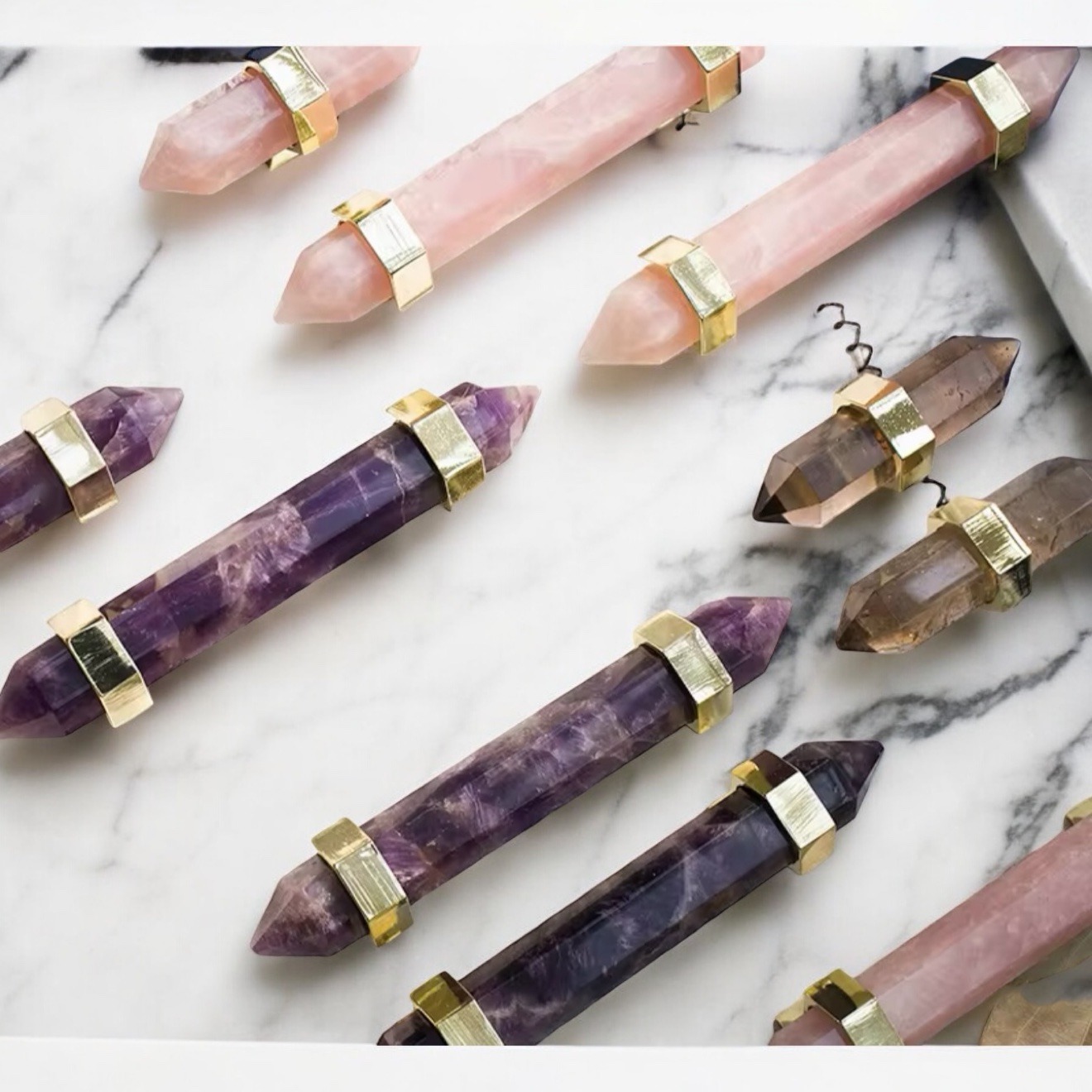 Crystal point cabinet pulls in rose quartz, amethyst and smoky quartz with gold mounts on white marble