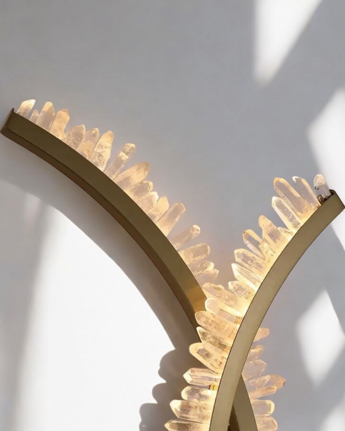 Clear quartz crystal wall light on curved gold arcs